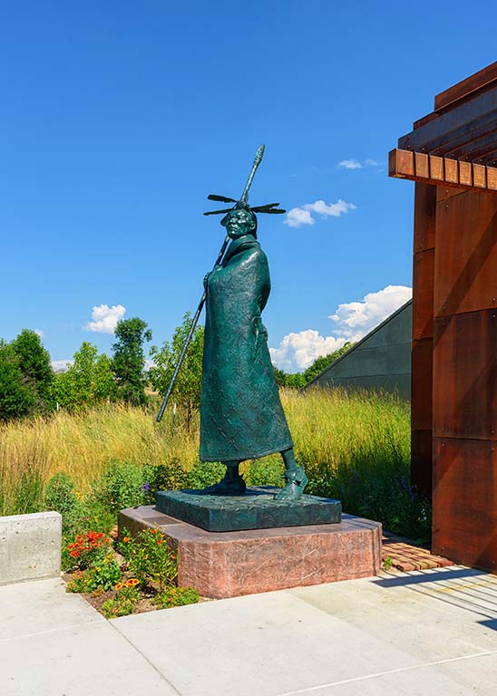 Large, bronze sculpture of an American Indian standing with a spear